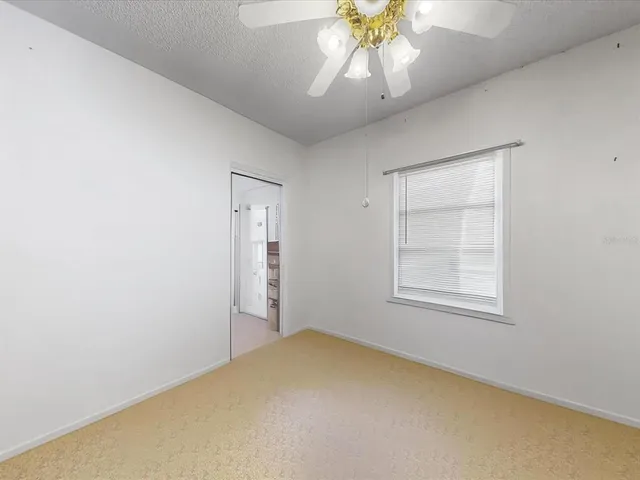 an empty room with a chandelier fan and windows
