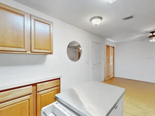 an empty room with a chandelier fan and windows