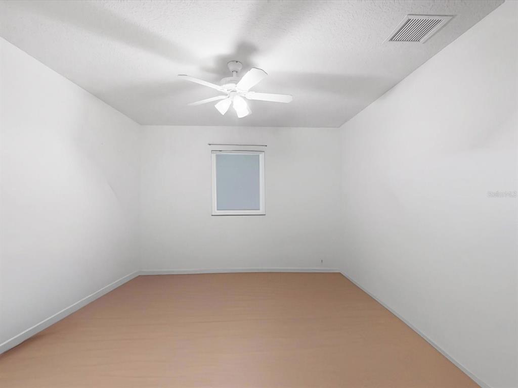420 Jacks Memorial Road St. Cloud, FL 34769 - Photo 22 of 37 an empty room with a chandelier fan and windows