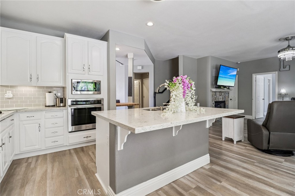 31461 Congressional Drive Temecula, CA 92591 - Photo 22 of 69 a large kitchen with kitchen island a sink dishwasher stove and white cabinets with wooden floor