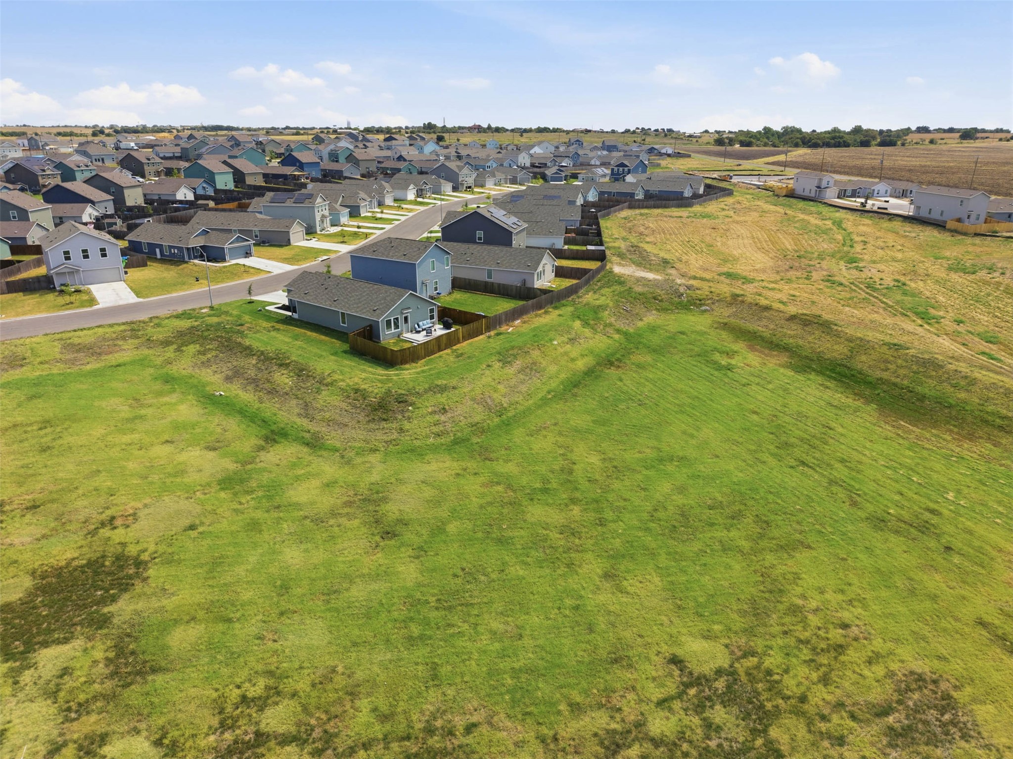 171 Cattle Queen Road Jarrell, TX 76537 - Photo 36 of 38 An aerial perspective showcases a neighborhood bordering an expansive green field.