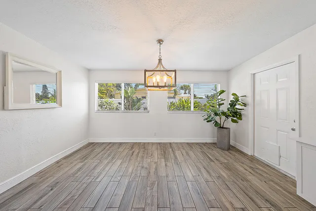 a view of a hallway with wooden floor and a chandelier