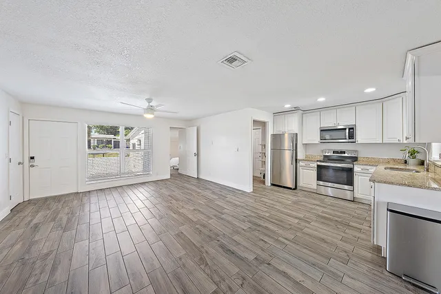 a view of a kitchen with wooden floor and electronic appliances