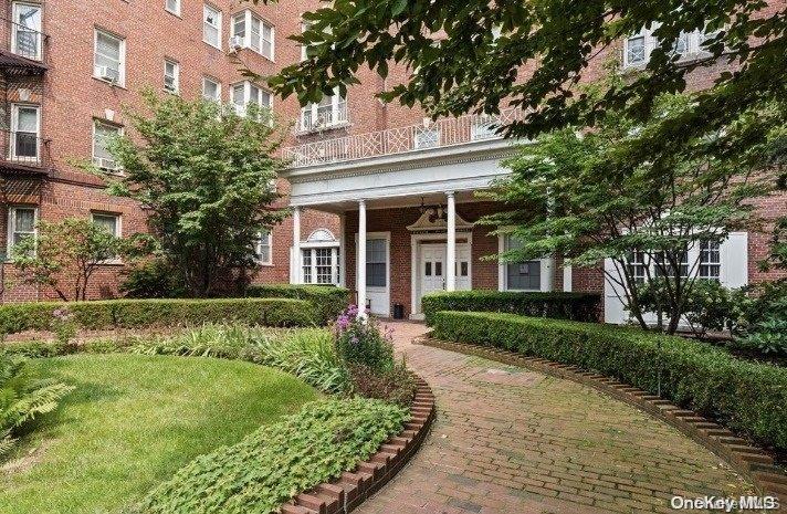 84-49 168th Street, Unit 6N Queens, NY 11432 - Photo 1 of 26 a view of a white house next to a yard with big trees