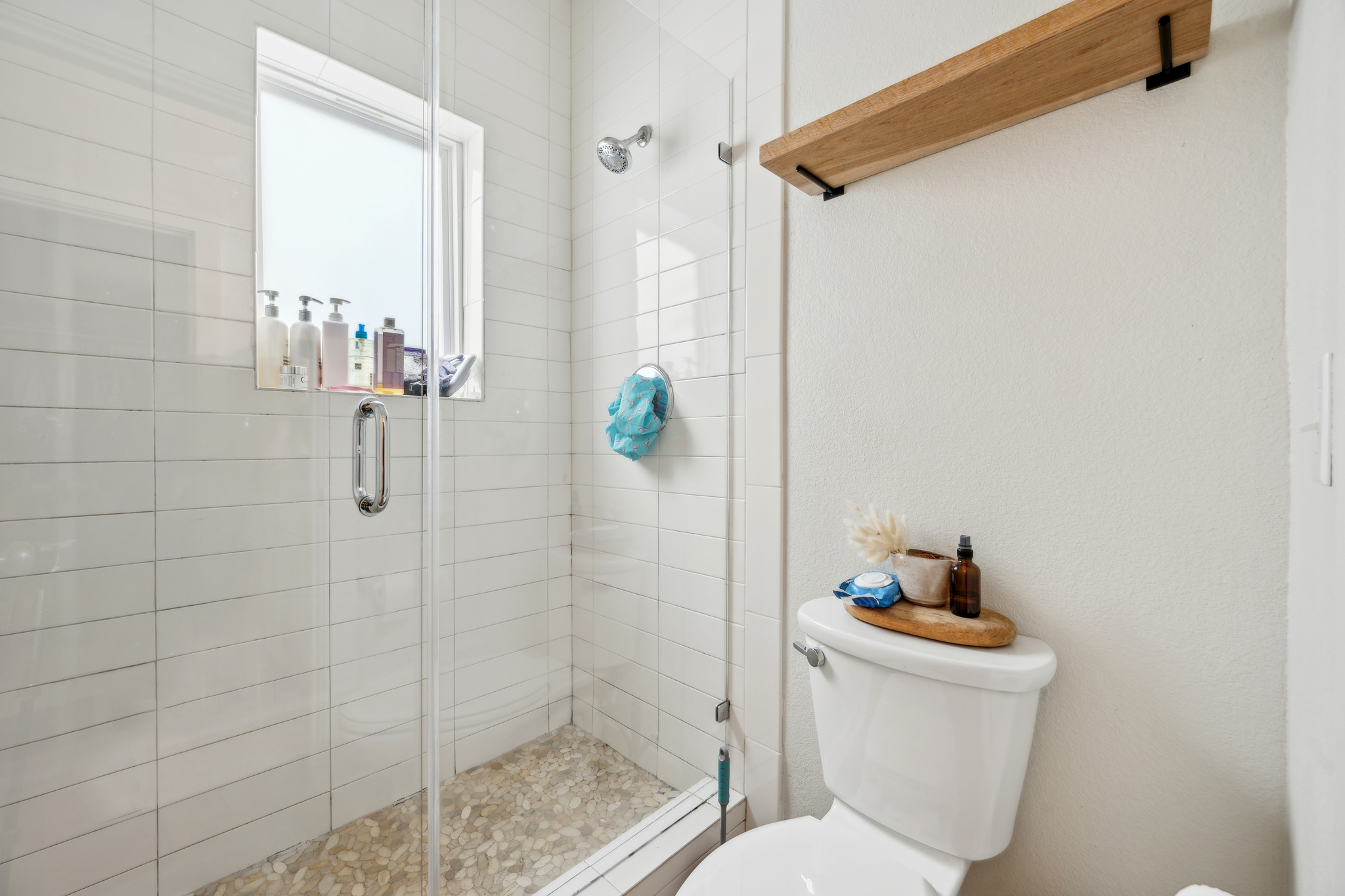 2827 Manor Road, Unit 3104 Austin, TX 78722 - Photo 14 of 30 A well-appointed shower space features white subway tile and a pebbled floor, beside a modern commode.
