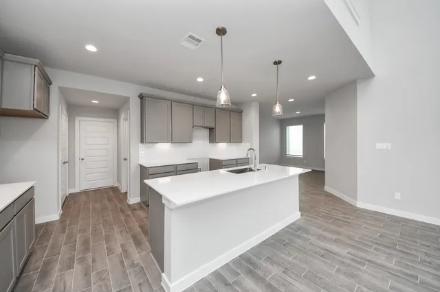 a large kitchen with kitchen island a stove a sink dishwasher and a refrigerator with wooden floor