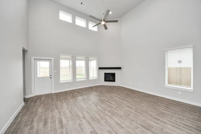 an empty room with wooden floor chandelier and windows