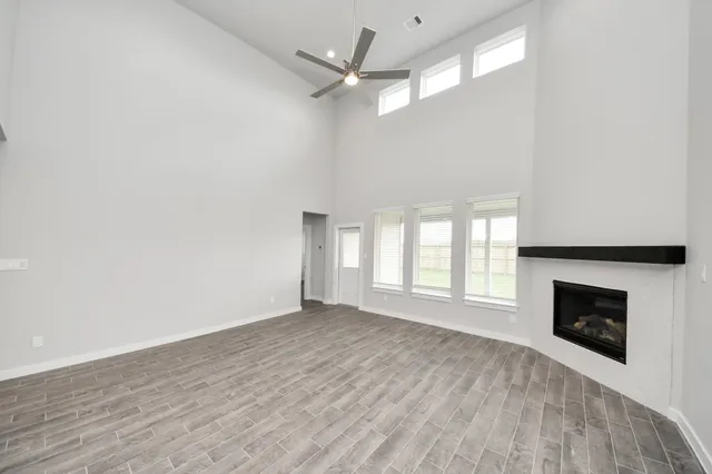 an empty room with wooden floor fireplace and windows