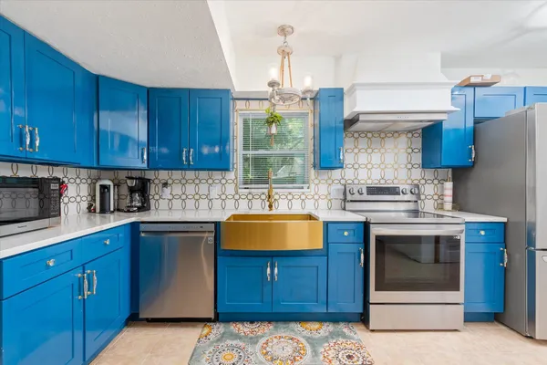 a kitchen with stainless steel appliances granite countertop a sink a stove and a wooden cabinets
