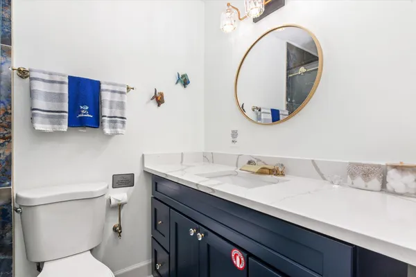 a bathroom with a granite countertop toilet sink and mirror