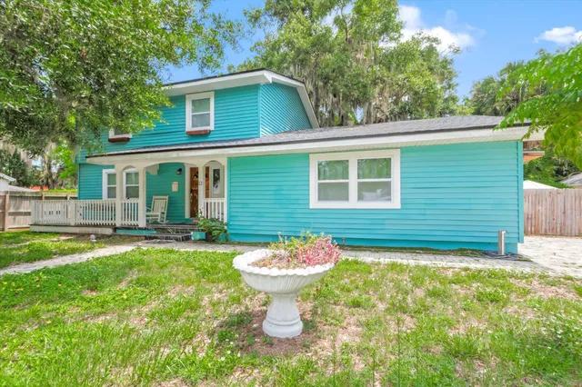 a view of house with a yard and potted plants