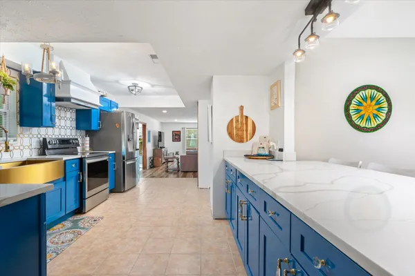 a kitchen with stainless steel appliances granite countertop a sink a stove top oven a chimney and a center island