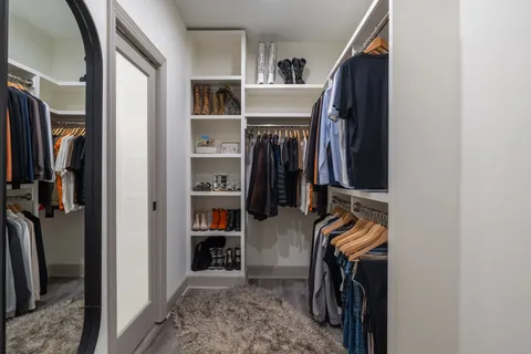 a view of walk in closet with clothes and shoes