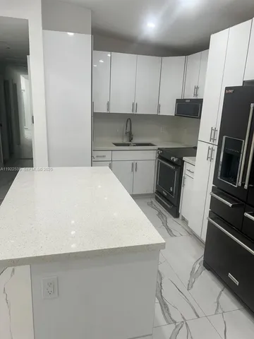 a kitchen with a sink a microwave a refrigerator and cabinets