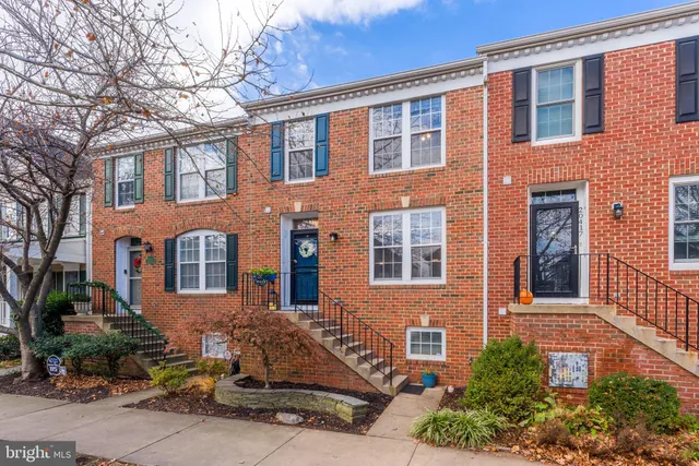 a view of an empty room with wooden floor and kitchen view