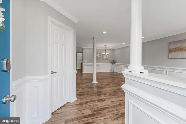 a view of an empty room with wooden floor and a kitchen