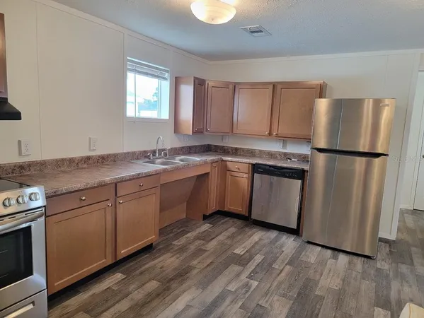 a kitchen with a sink a refrigerator and wooden floor