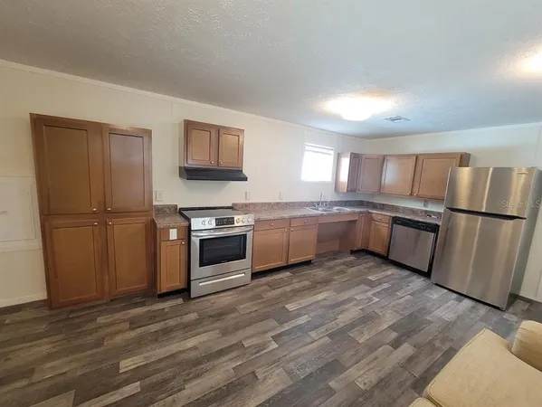 a kitchen with granite countertop a refrigerator and a stove top oven