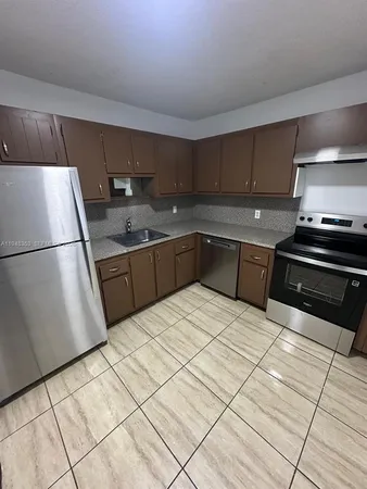 a kitchen with granite countertop a refrigerator and a sink