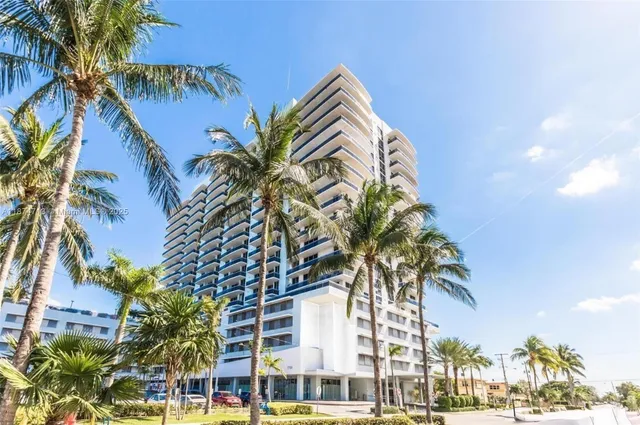 a front view of multi story residential apartment building with yard and sign board