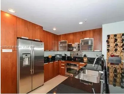 a kitchen with stainless steel appliances granite countertop a refrigerator a stove a sink a dining table and chairs with wooden floor