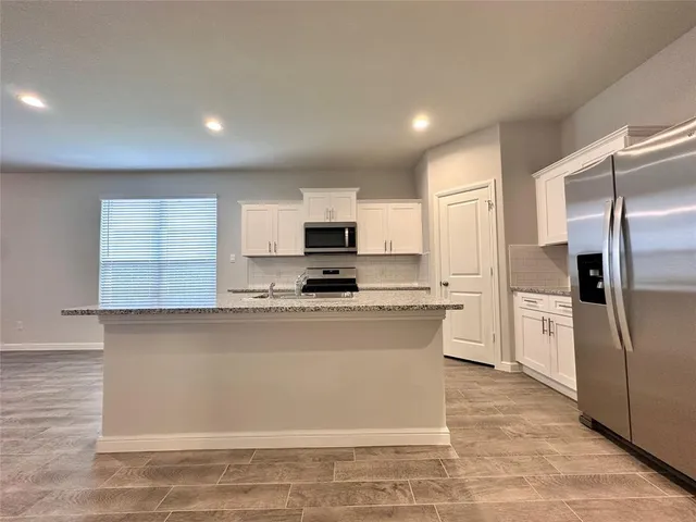 a kitchen with stainless steel appliances granite countertop a refrigerator sink and microwave