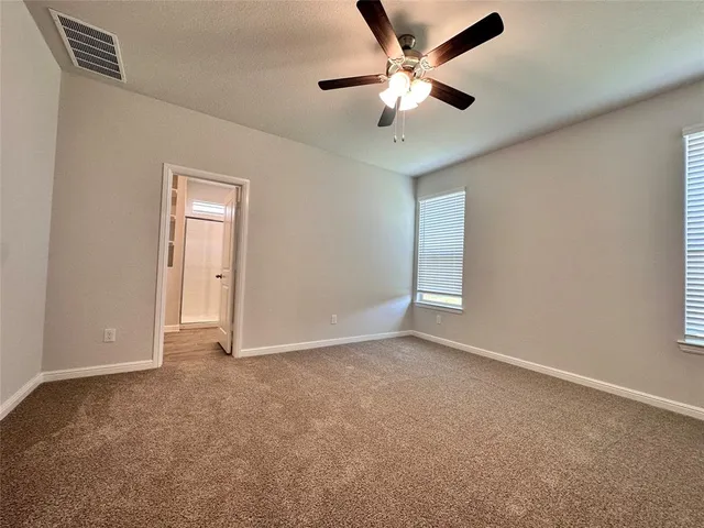 an empty room with chandelier fan and windows