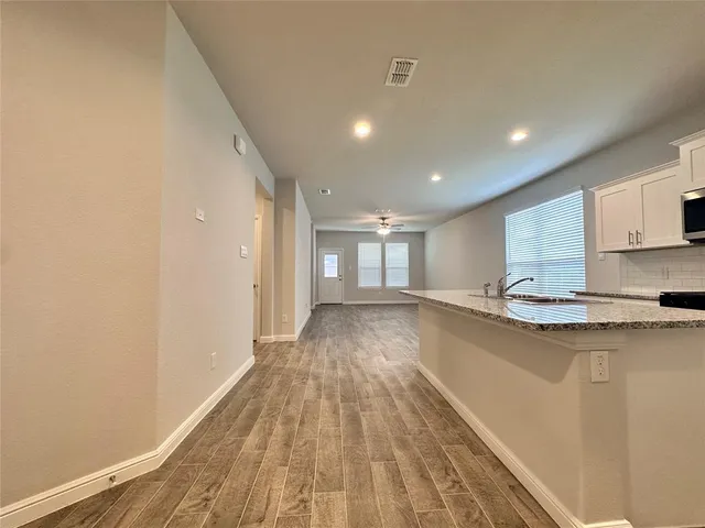 a view of a kitchen with kitchen island a sink wooden floor and a refrigerator