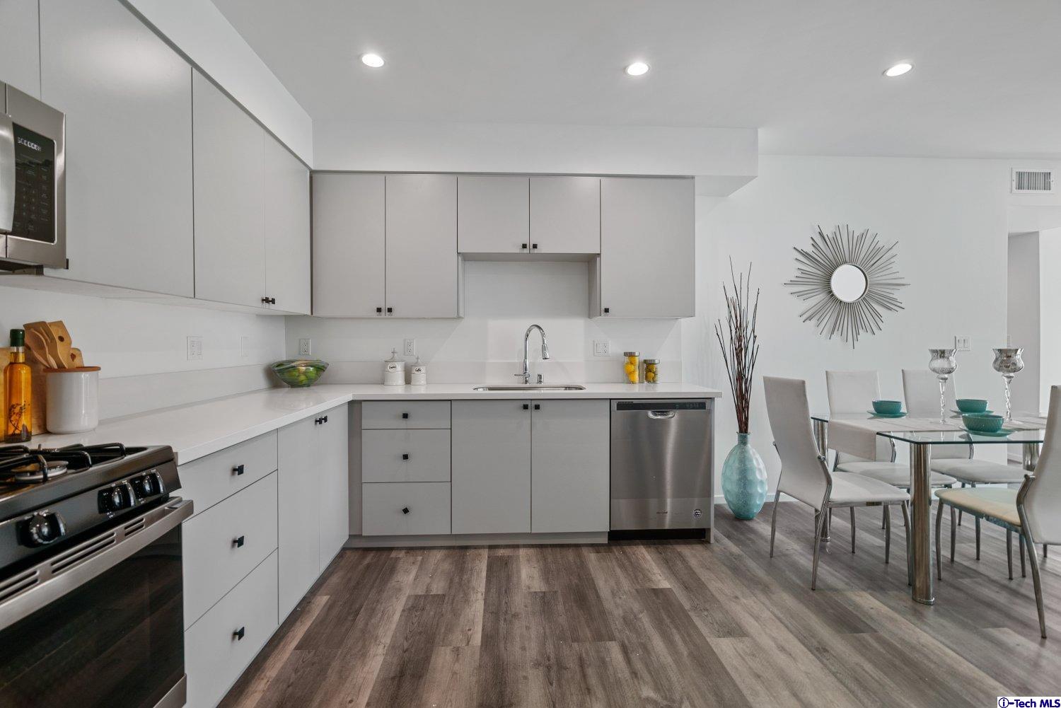 7064 Greeley Street, Unit 102 Tujunga, CA 91042 - Photo 9 of 27 a kitchen with a stove a sink and white cabinets with wooden floor