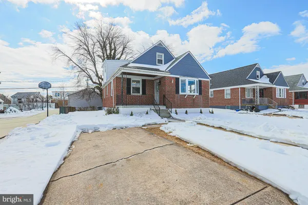 a front view of a house with a yard covered with snow and cars
