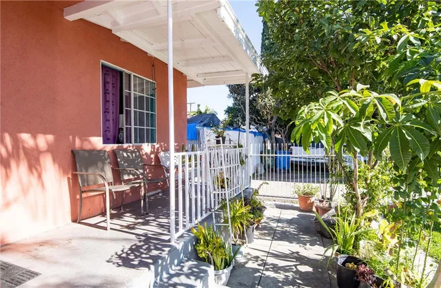 a balcony with table and chairs and potted plants