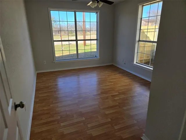 an empty room with wooden floor and windows