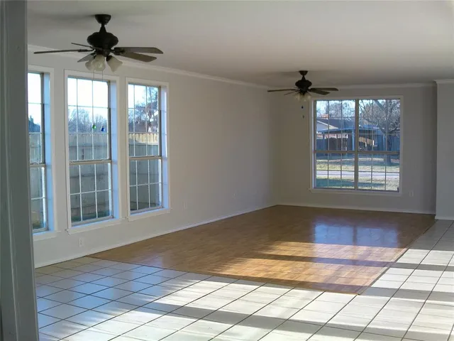 a view of an empty room and window and chandelier fan