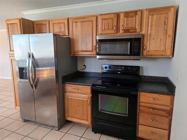 a kitchen with granite countertop a refrigerator stove and microwave