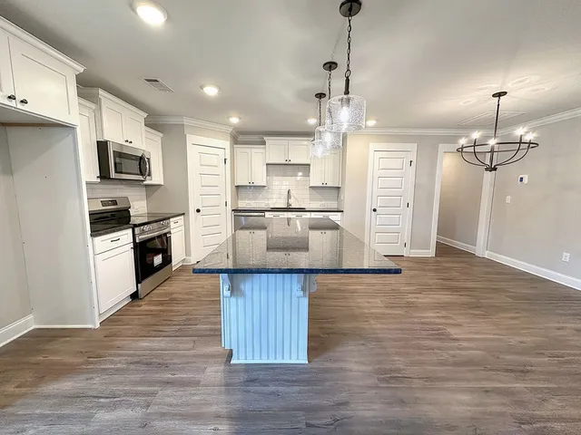 a kitchen with stainless steel appliances kitchen island hardwood floor sink and stove