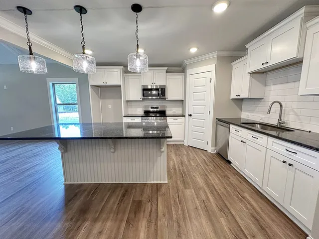 an empty room with chandelier fan and windows