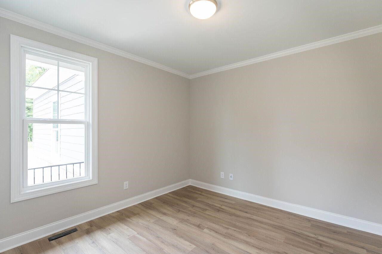 9616 Chris Drive Raleigh, NC 27603 - Photo 14 of 42 an empty room with wooden floor and windows