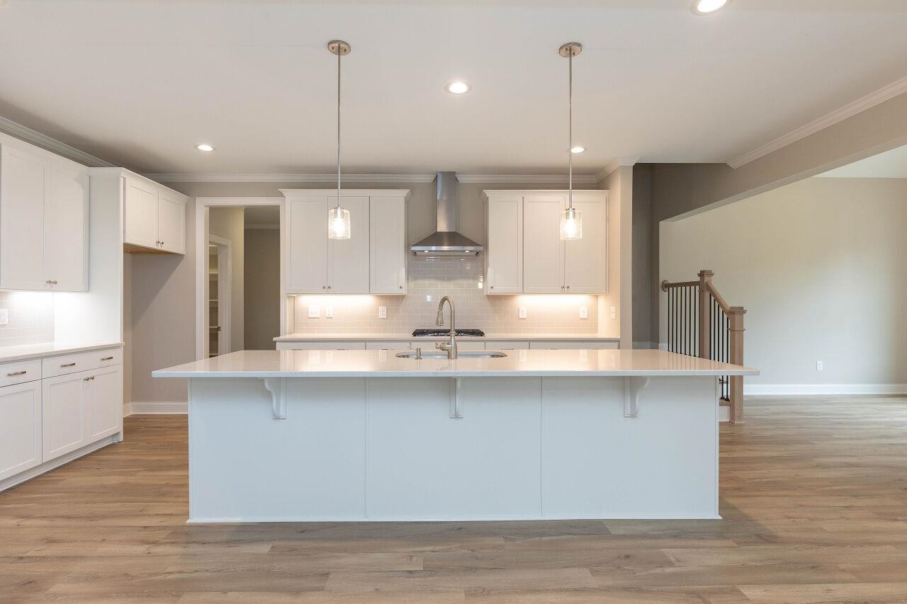 9616 Chris Drive Raleigh, NC 27603 - Photo 21 of 42 a large kitchen with granite countertop a stove a sink a refrigerator and white cabinets with wooden floor