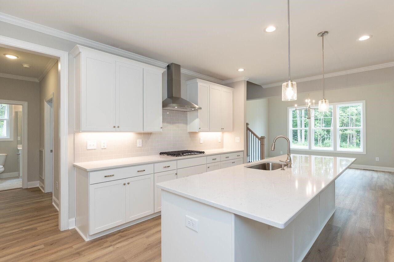 9616 Chris Drive Raleigh, NC 27603 - Photo 22 of 42 a kitchen with a stove a sink a wooden floor and a window