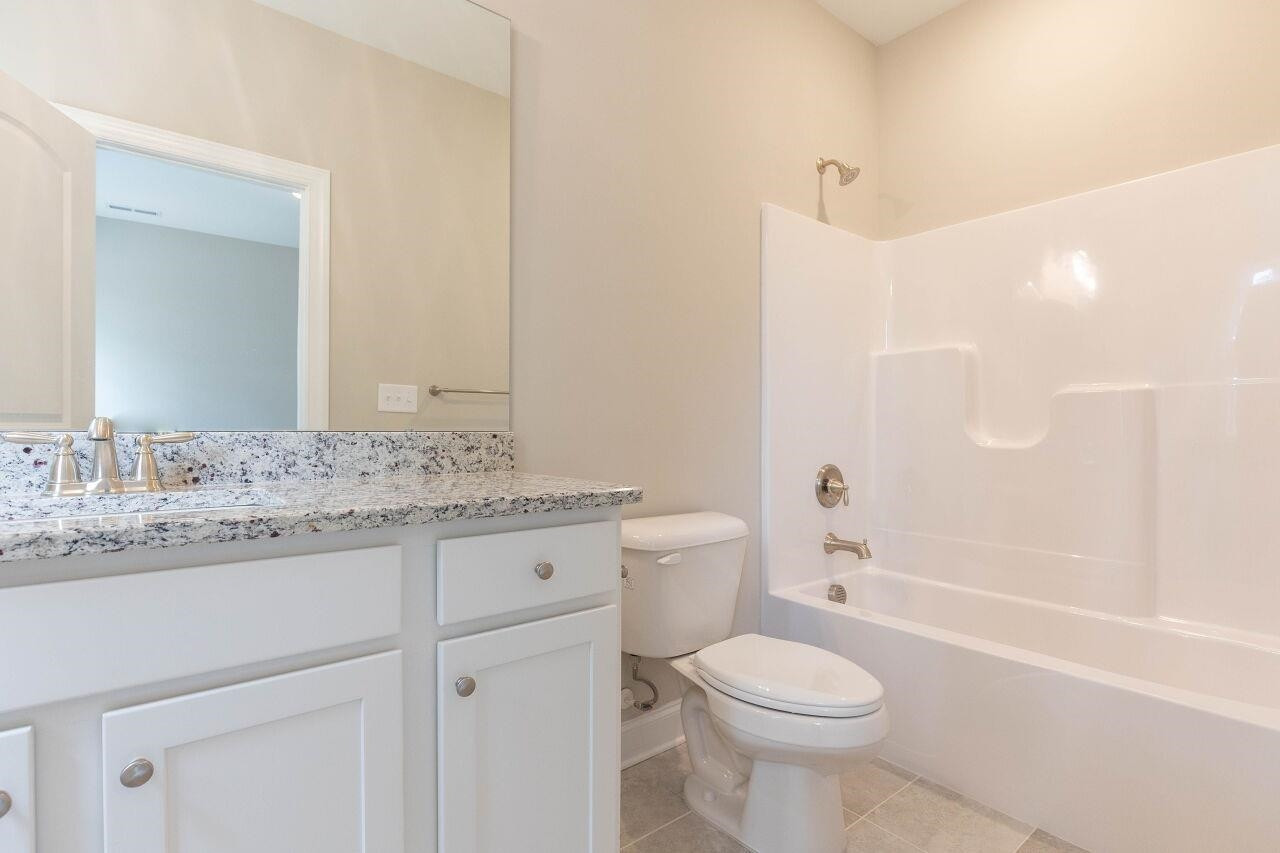 9616 Chris Drive Raleigh, NC 27603 - Photo 38 of 42 a bathroom with a granite countertop toilet a sink and a bathtub