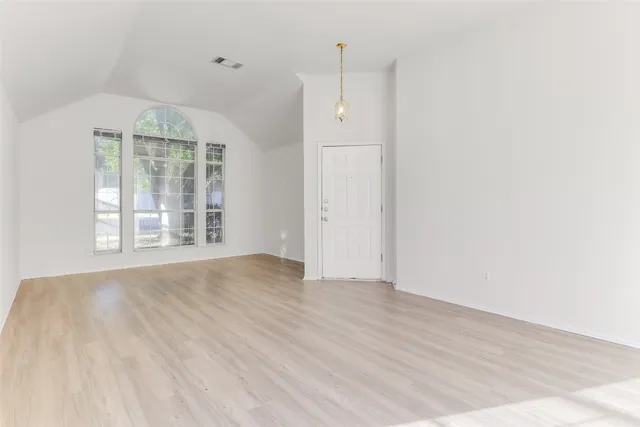 an empty room with wooden floor cabinet and windows