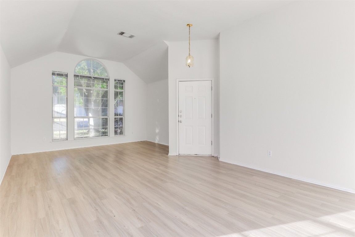 15437 Ozone Place Austin, TX 78728 - Photo 3 of 21 an empty room with wooden floor cabinet and windows