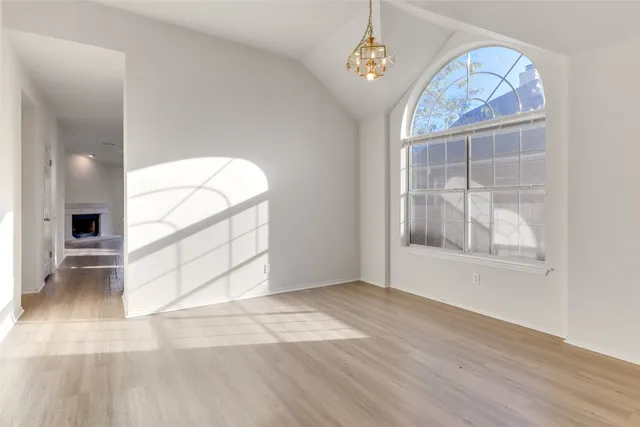 an empty room with wooden floor cabinet and windows