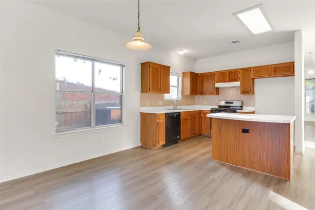 a kitchen with stainless steel appliances granite countertop a stove a sink dishwasher and a refrigerator with wooden floor