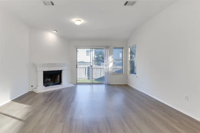 an empty room with wooden floor fireplace and windows