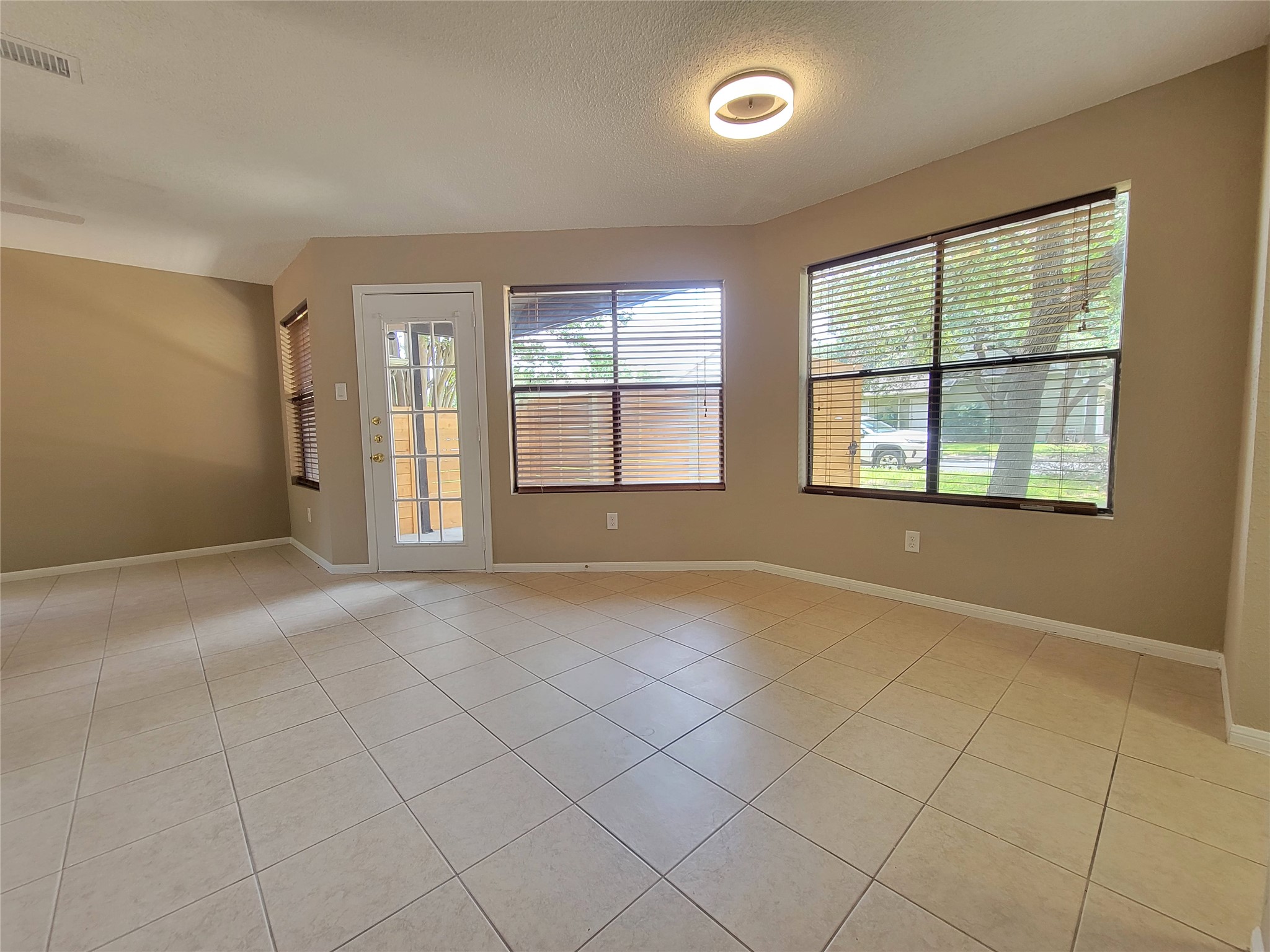 8706 Schick Road, Unit A Austin, TX 78729 - Photo 7 of 33 A well-lit living area features tiled flooring and ample natural light from multiple windows and a glass-paneled door.
