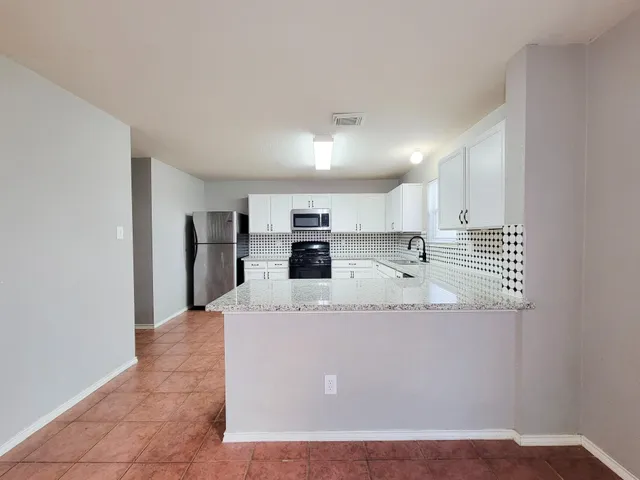 a large white kitchen with kitchen island a sink stainless steel appliances and a refrigerator