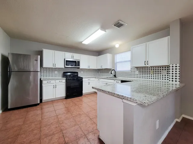 a kitchen with stainless steel appliances granite countertop a sink stove refrigerator and cabinets
