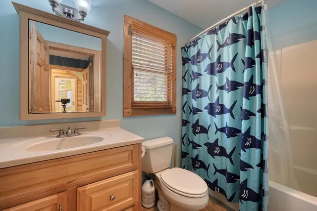 a view of an empty room with wooden floor fireplace and a window