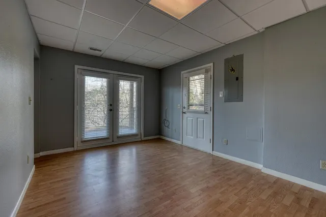 an empty room with wooden floor and windows